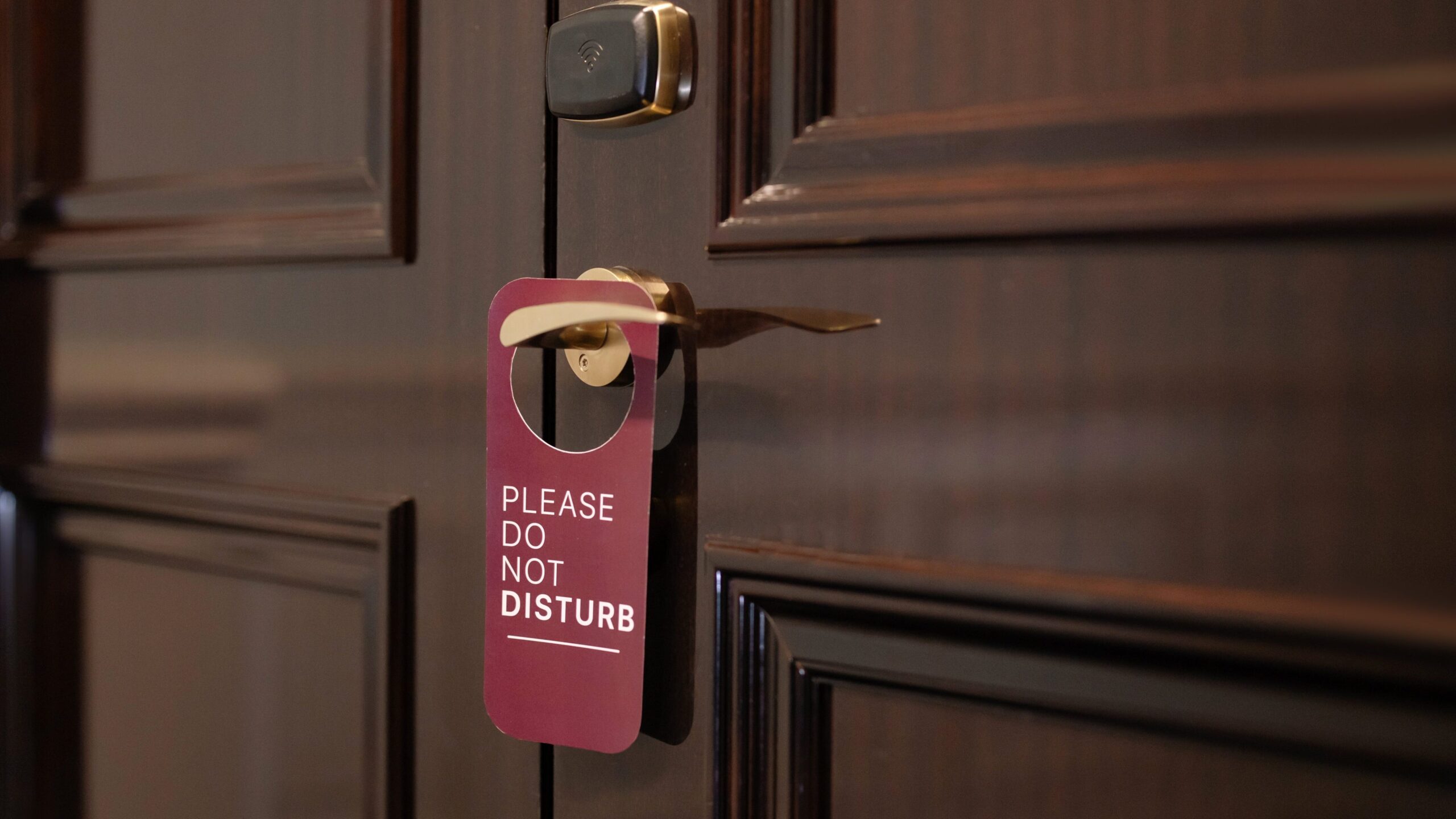 Hotel room door with a please do not disturb sign hanging on the handle, emphasizing guest privacy